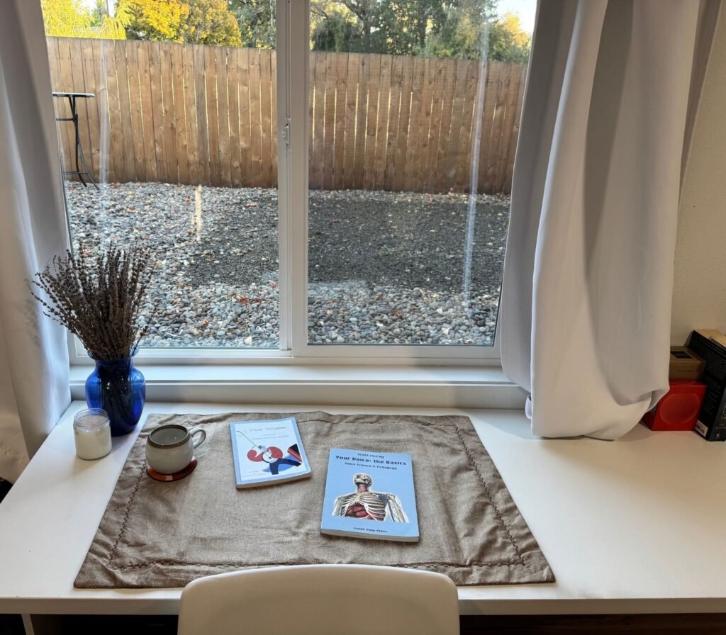 Image of Amanda's teaching studio and desk and vocal health books.